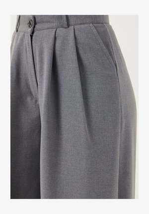 Pantalon gris taille haute avec plis sur le devant, poches latérales, passants pour ceinture et fermeture par bouton, présenté de la taille jusqu'au milieu des cuisses.