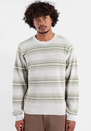 Pull-over en maille avec des rayures horizontales vertes et crème, col rond, et poignets côtelés. Présente un patch logo discret sur la poitrine.