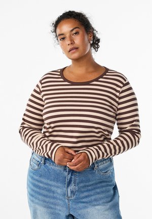 Long-sleeve striped ribbed top in brown and cream, round neckline, featuring extended sleeve cuffs, paired with light blue denim jeans.