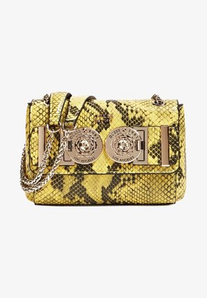 Bolso con estampado de serpiente en amarillo y negro, con una correa de cadena y dos grandes cierres redondos en tono dorado con el logo de Guess en el frente.