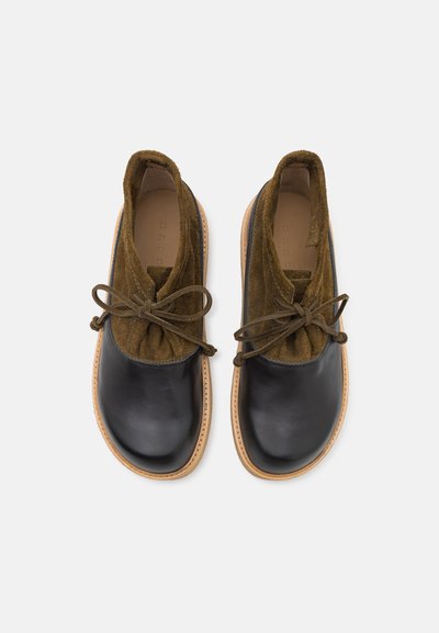 Schwarze Lederschuhe mit olivgrünen Suede-Obermaterialien, gerundeter Spitze und Schnürdesign. Natürliche, beige Gummisohle und Nahtdetails.