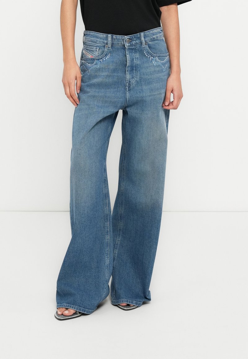 Μπλε τζιν παντελόνι με φαρδιά μπατζάκια και διακοσμητικές ραφές στις τσέπες, κατασκευασμένο από τζιν ύφασμα. Διαθέτει ψηλή μέση και άνετη εφαρμογή, συνδυασμένο με μαύρο τοπ.