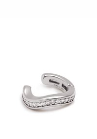Anillo plateado con un diseño suave y curvado, con una fila de piedras preciosas transparentes incrustadas en un lado. Acabado de metal pulido, forma abierta.