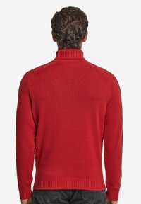 Röd stickad tröja med hög hals och ribbade ärmslut, med en mjuk textur och en figurnära silhuett, sedd bakifrån.