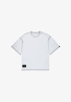 Fehér, rövid ujjú póló szürke varrással, kerek nyakkivágással, és fekete címkével az alsó bal sarokban "STUDIO EDITION" felirattal.