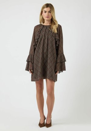 Vestito marrone a scacchi con maniche arricciate, scollo rotondo e vestibilità ampia. Indossato con scarpe con tacco marroni. Tessuto liscio con motivo a quadretti.