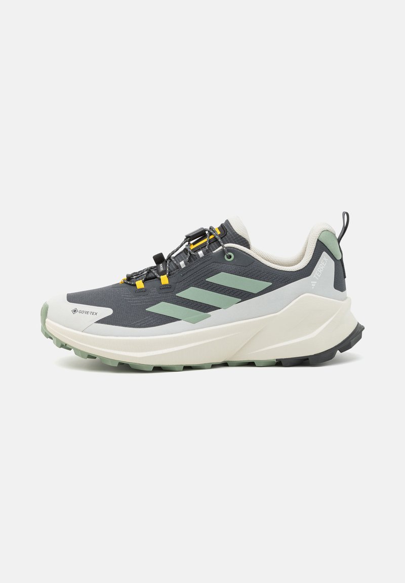 W ciemnoszarym i jasnozielonym kolorze but do biegania po trailu Adidas z białą podeszwą, wyściełanym kołnierzem, etykietą Gore-Tex i bezpiecznym systemem blokady sznurowadeł.