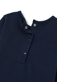 Dunkelblaues Stoffhemd mit einer Nahaufnahme des Kragens, auf dem zwei Druckknöpfe geschlossen und zwei offen sind, auf einem weißen Hintergrund.