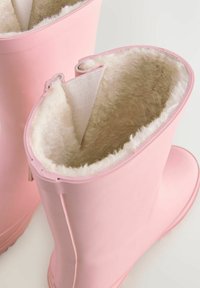 Stivali di gomma impermeabili rosa con un rivestimento beige morbido e peloso e un'esterno liscio. Design con parte superiore aperta e leggero risvolto.