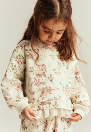 Blomsteragteret, cremefarvet sweatshirt med lange ærmer, ribbadde manchetter og en dekorativ blonderemse i kanten. Blødt bomuldsblandingsmateriale.