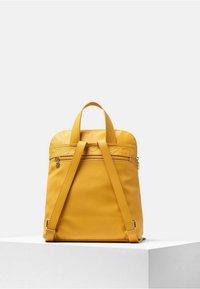 Yellow leather backpack with a smooth texture, dual top handles, and adjustable straps. Features a zippered compartment and subtle design accents.