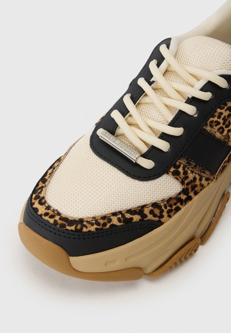 Sneaker con stampa leopardata, parte superiore in rete beige e dettagli in sintetico neri. Presenta lacci crema e una suola in gomma con grip testurizzato.
