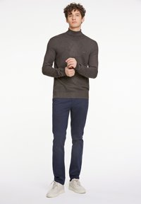 Mörkgrå turtleneck-tröja, slim fit, tillsammans med marinblå byxor. Outfiten inkluderar off-white sneakers i casual design, med slät textur.