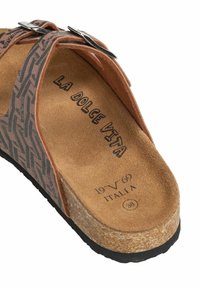 Bruine sandalen met patroon, voorzien van een kurken voetbed en een zwarte rubberen zool. Verstelbare zilveren gespen op de banden, met "LA DOLCE VITA" branding aan de binnenkant.