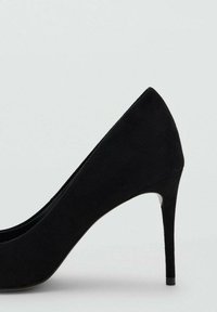 Zapato de tacón alto negro con punta puntiaguda y textura suave de ante. Cuenta con un tacón delgado y alto y un diseño minimalista sin adornos.