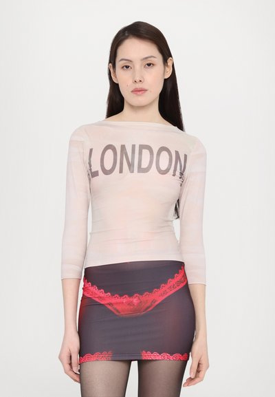 Sheer long-sleeve top printed with "LONDON" in dark letters, paired with a dark skirt featuring a red lace print at the hem and an undergarment design.