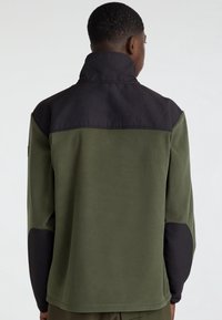 Fleecejack met een hoge kraag, met een groen lichaam en zwarte schouderpanelen. Gladde textuur, minimale stiksel details.