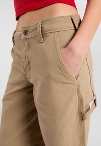 Khaki cargobroek met een relaxte pasvorm, uitgerust met een knoopsluiting, zijzakken en een textielachtige katoen stof.