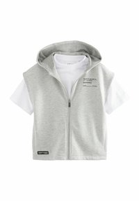 Lys grå hættevest med lynlås over en hvid t-shirt. Har et trykt mærke på vesten og en sort accentmærke forneden.