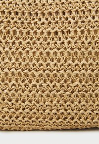 Panier de rangement tissé en matériau naturel, de couleur beige clair, avec un motif entrelacé et une surface texturée aux bords arrondis.