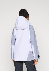 Lahka, dvobarvna jakna z belo telo in sivimi rokavi, opremljena s kapuco, nastavljivimi manšetami in zračno teksturo tkanine.