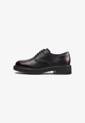 Chaussure habillée en cuir noir à lacets avec semelle épaisse et petit talon, vue de côté sur fond blanc.
