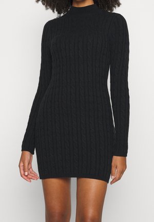 Robe noire en maille avec manches longues, col haut et motif en torsades texturé. Silhouette ajustée, ourlet et poignets côtelés.