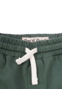 Gröna shorts med elastisk midja och vit dragsko. Har en etikett sydd på midjan. Tyget verkar mjukt och med en enkel design.