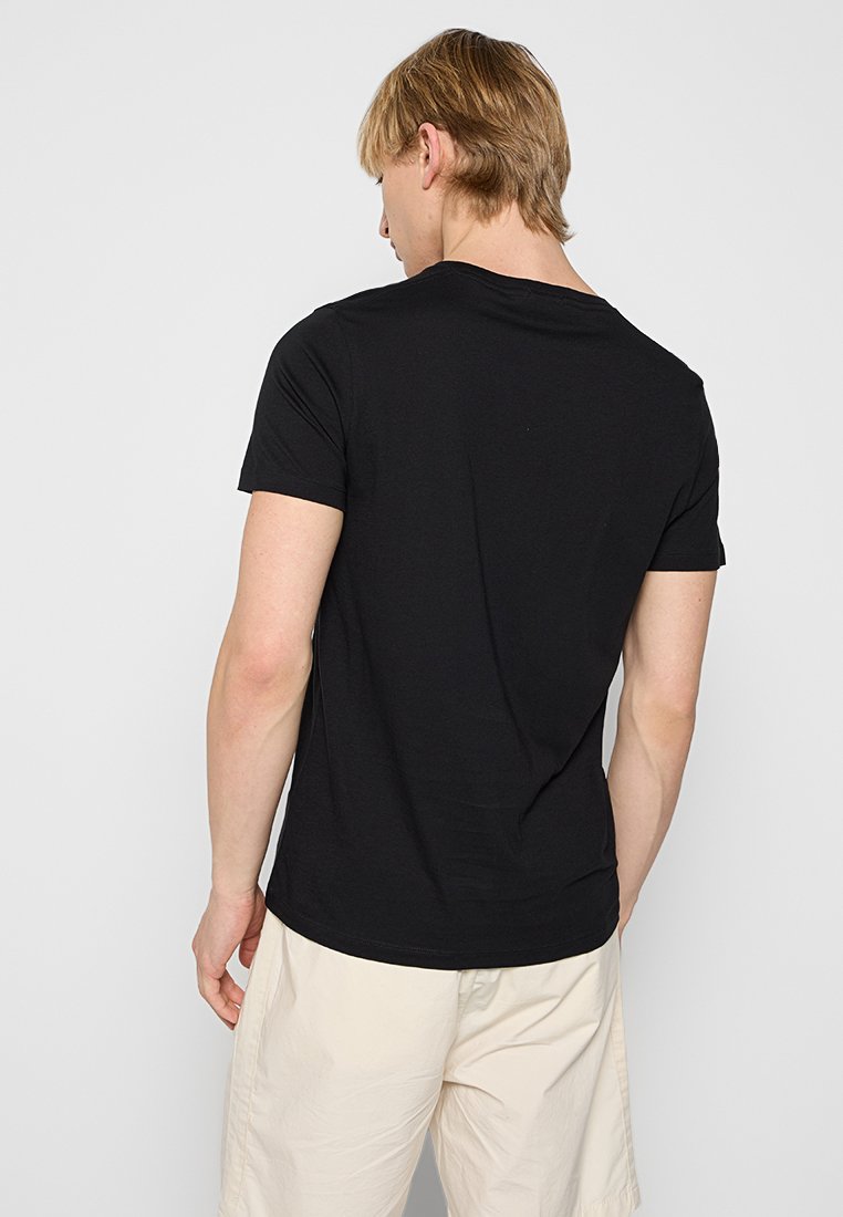 Schwarzes T-Shirt mit kurzen Ärmeln aus glattem Baumwollstoff, mit einem runden Halsausschnitt und einer figurschmeichelnden Passform. Tragen mit hellen Shorts.