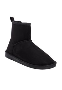 Botín negro de tobillo hecho de un material suave similar al ante. Presenta una punta redondeada, costuras decorativas y una suela de goma plana y texturizada.