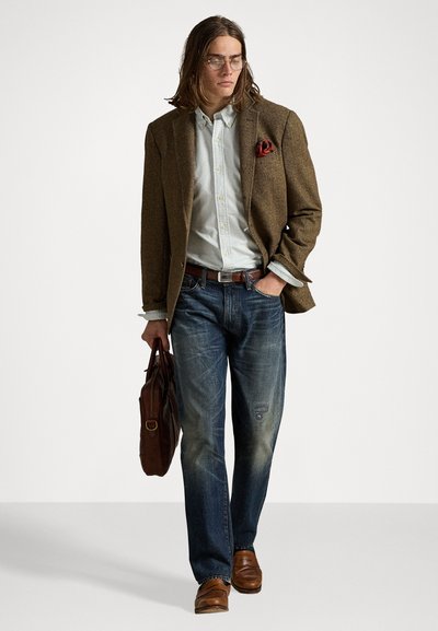 Blazer en tweed marron sur une chemise rayée claire, jeans bleus, chaussures en cuir marron et un sac en cuir marron. Comprend un pochettes rouge.