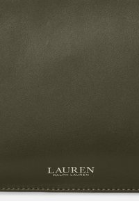 Mörkgrön läderyta med fin textur och "LAUREN Ralph Lauren"-logotypen präglad i vitt nära nedre kanten.