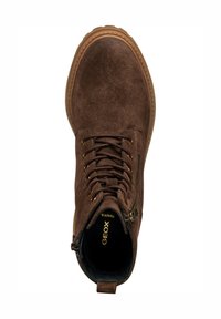 Stivale alla caviglia in suede marrone con punta rotonda, allacciatura frontale e zip laterale. Presenta dettagli in oro e una suola in gomma beige.