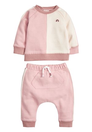 Småbarns tofarvede lyserøde og cremefarvede langærmede sweatshirt med lille broderet regnbue og matchende lyserøde bukser med elastik i taljen og snøring.