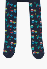 Navy tights featuring a colorful tractor pattern in red, blue, green, and yellow, interspersed with small stars. Soft knit texture.