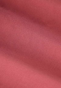 Zachte, gladde stof in een stofroze kleur met zachte plooien en subtiele textuur die zichtbaar is over het oppervlak.