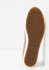 Zapatillas de ante marrón con una entresuela blanca flexible y una suela exterior de goma texturizada que presenta un patrón ondulado y la marca "Gabor".