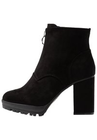 Botín negro de ante con un alto tacón cuadrado, que cuenta con un cierre de cremallera lateral y un patrón de surcos texturizados en la suela para mayor tracción.