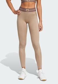 Leggings beige con vita alta caratterizzati da un design a righe marroni. Texture liscia con accenti a coste diagonali sulle gambe inferiori.