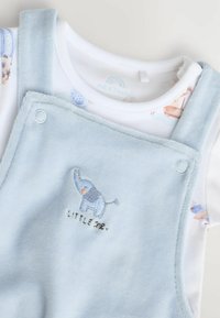Zacht blauw babypak met geborduurd olifantje en de tekst "Little One", gelaagd over een witte romper met baby-thema prints.