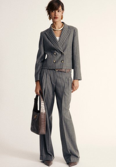Grijze gestreepte double-breasted blazer met bijpassende high-waisted broek, textuur bruin faux-krokodillenhandtas, en puntige hakken.