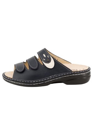 Sandale noire à bout ouvert, à enfiler, avec trois brides réglables en velcro et une couture blanche le long du bord de la semelle.