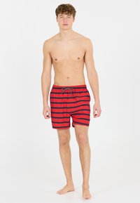 Shorts de bain rayés rouges et bleu marine avec une taille élastique et un cordon de serrage. Fabriqués en tissu léger, adaptés pour la baignade.