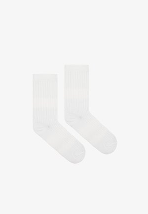 Białe bawełniane skarpetki o pionowej prążkowanej fakturze, długości do połowy łydki, ze wzmocnionym palcem i miękkimi elastycznymi mankietami. Miękki i oddychający materiał.