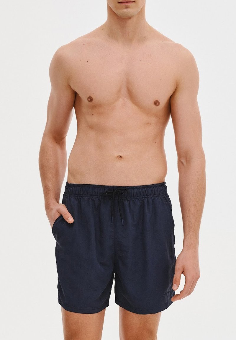 Granatowe szorty pływackie z elastycznym paskiem, sznurkiem do regulacji i bocznymi kieszeniami; wykonane z lekkiego materiału o gładkiej fakturze.