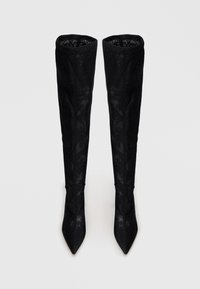 Botas negras por encima de la rodilla, hechas de material texturizado, con punta afilada y un ajuste ceñido, con sutiles patrones florales visibles.