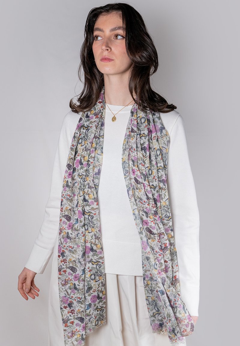 Let floralmønstrede letvægts tørklæde i blød, gennemsigtig stof, der har multicolore blomster på en lys baggrund, draperet omkring modellens hals.
