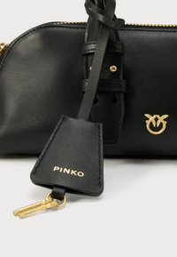 Mala de pele preta com ferragens douradas, com fecho de correr e etiqueta com o nome da marca "PINKO". Textura lisa e design minimalista.