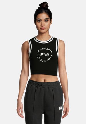 Top deportivo negro recortado con rayas ribeteadas blancas y el logo y texto de Fila. Tela suave con un diseño sin mangas. Combinado con pantalones de chándal grises.