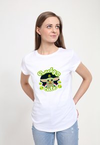 Biała koszulka z graficznym wzorem zawierającym tekst "Szczęśliwy i Uroczy" oraz ilustrację postaci z dużymi uszami i kolorowymi akcentami.